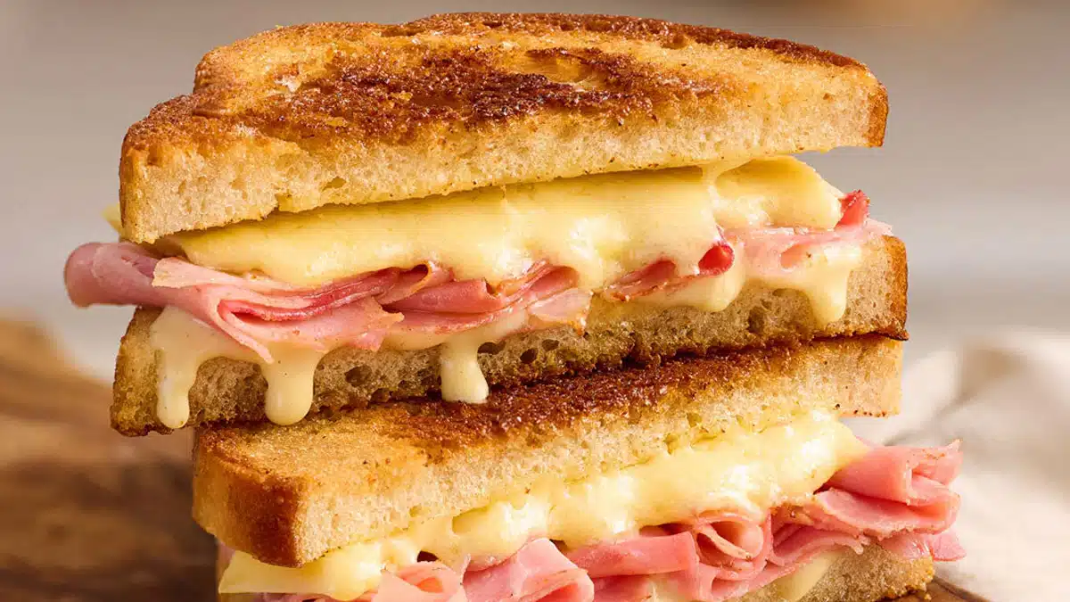 Croque-monsieur maison avec pain doré croustillant, jambon et comté fondant qui dégouline, sandwich grillé en gros plan